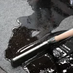 Placement produit schütz liquide d'étanchéité pour réparation et protection de roofing sur toiture. La raclette disperse le liquide d'étanchéité